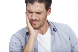 Man holding his jaw in pain from severe toothache, isolated on white