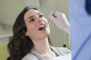 Closeup of dentist examining young woman's teeth