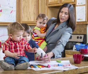 A mother in the kitchen plays with her chilrdren