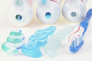 Three types of toothpaste in tubes with toothbrush