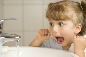 Cute girl cleaning teeth by floss