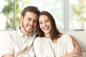 Happy couple sitting on a couch at home and looking at camera