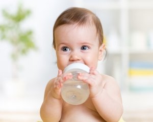 sweet baby girl holding bottle and drinking water