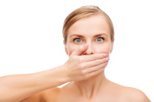 health and beauty concept - clean face of beautiful young woman covering her mouth with hand