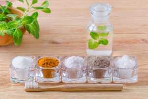 alternative natural mouthwash with mint, toothpaste xylitol or soda, turmeric - curcuma, himalayan salt, clay or ash, coconut oil and wood toothbrush, on wooden background
